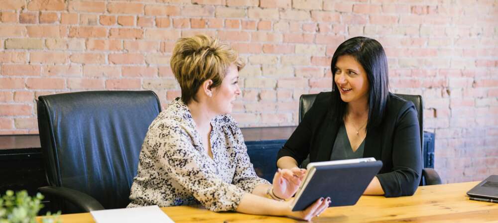 two women sitting on leather chairs in front of table
