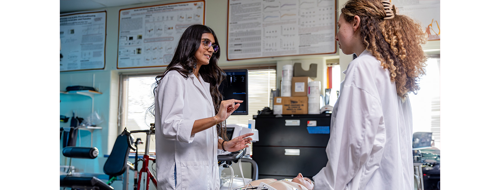 Two students wearing whit lab coats in medical lab class in conversation