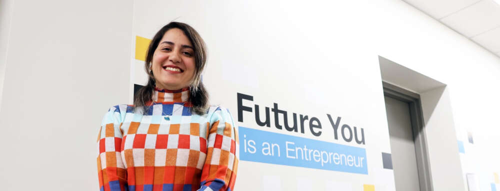 person in a patterned sweater stands in front of a white wall with the words "future you is an entrepreneur"