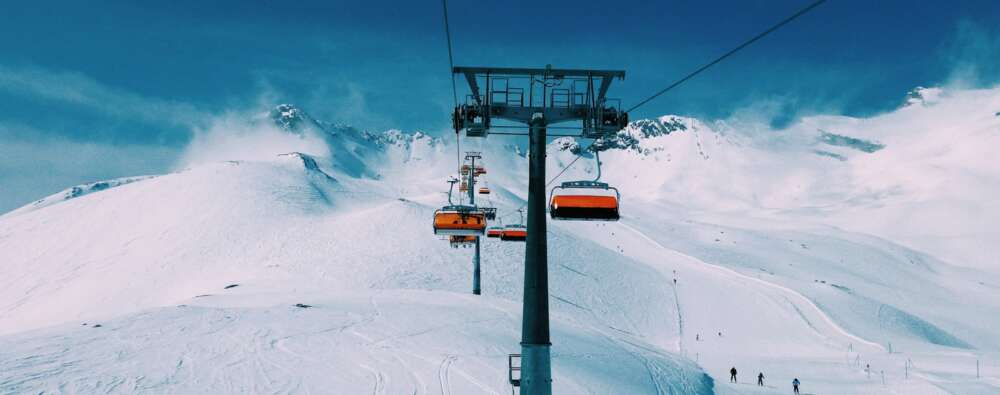 a ski lift going up the side of a snow covered mountain