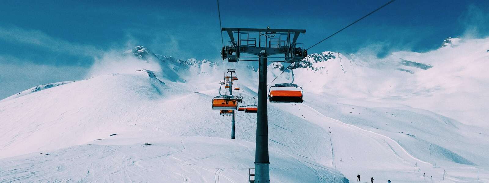a ski lift going up the side of a snow covered mountain