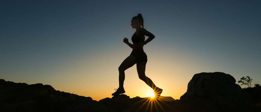 silhouette of man jumping on rocky mountain during sunset