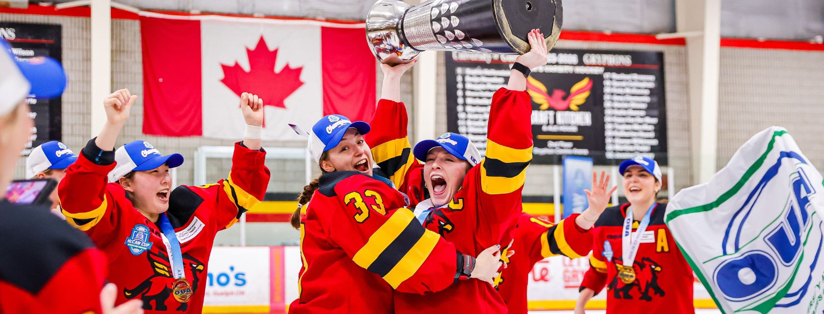 skaters in red jerseys and blue hats celebrate with a silver cup