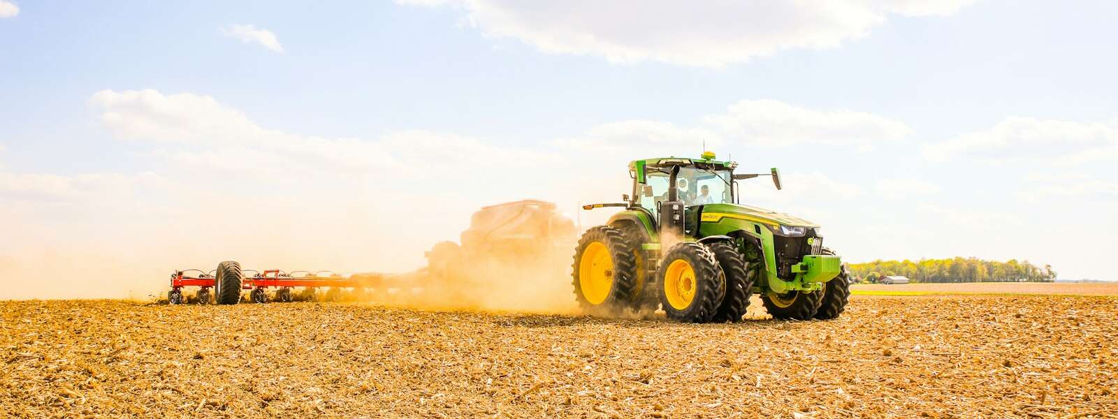 a tractor is plowing a field with a trailer